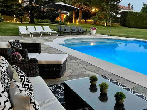 a swimming pool with chairs and a table next to it at Autentico lujo, Villa Stylish Host Cantabria. in Camargo