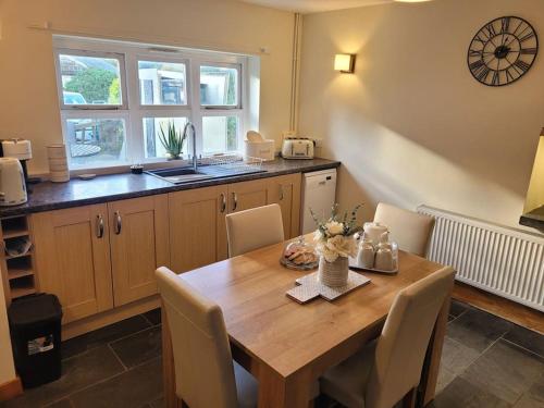 a kitchen with a wooden table with chairs and a sink at Cosy modern cottage by the sea, heart of snowdonia in Llwyngwril