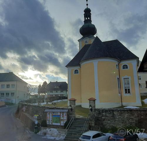 a church with a steeple on top of a building at Jogilation in Sankt Jakob im Walde