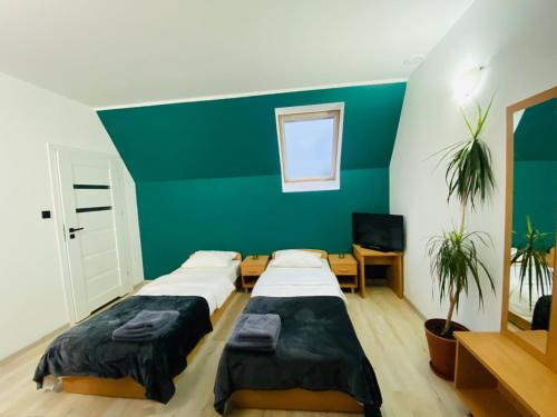 twee bedden in een kamer met een groene muur bij HOTEL MILO - Noclegi Bartoszyce in Bartoszyce