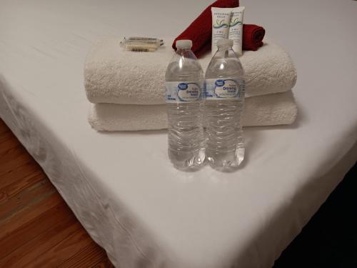 The Top-Floor at Centerdale Village Room B* Private Room في North Providence: زجاجتان من الماء يجلسون على منضدة مع المناشف
