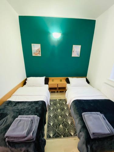two beds in a room with a green wall at HOTEL MILO - Noclegi Bartoszyce in Bartoszyce