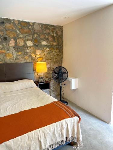 1 dormitorio con cama y pared de piedra en Cabaña El Fantasio en Villa Carlos Paz