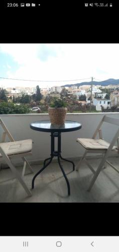 una mesa con 2 sillas y una maceta en el balcón en Iokasti studio 4, en Ándros