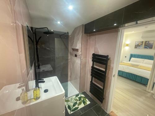 a bathroom with a shower and a sink and a bed at Stylish Studio in Colchester