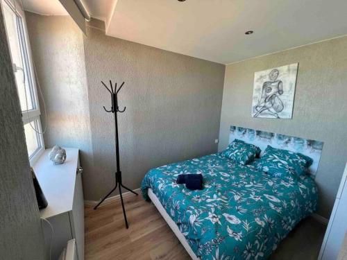 een slaapkamer met een bed met een blauw dekbed bij Coquet F1 calme lumineux centre ville (Netflix) in Saint-Étienne