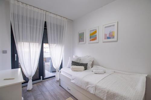 a white bedroom with a bed and a window at Penthouse Apartman Roko in Virovitica