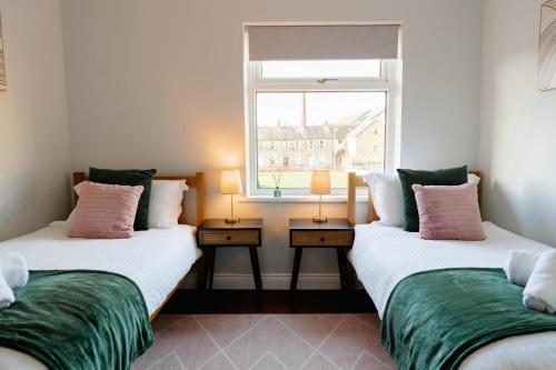 two twin beds in a room with a window at Bowling View - Stylish, Home from Home in Skipton in Skipton