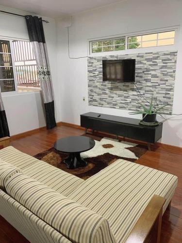 a living room with a couch and a flat screen tv at Kapowlito Real Estate Casa Hoopweg in Paramaribo