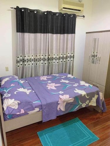 a bedroom with a bed with a purple comforter at Kapowlito Real Estate Casa Hoopweg in Paramaribo