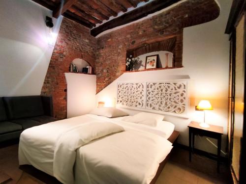 a bedroom with a white bed and a brick wall at Giada Palace Group - Sweet City Center Apartment in Lucca