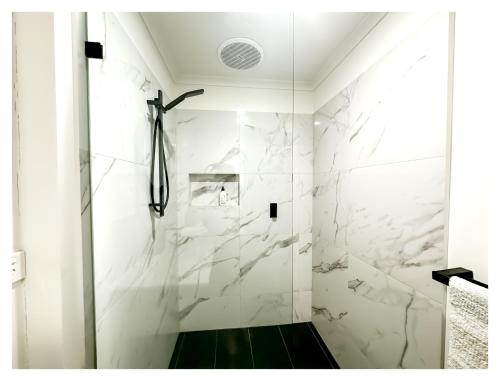 uma casa de banho com chuveiro e paredes em mármore branco em HAVEN: Stunning Unley *history*location*charm 3bd em Unley