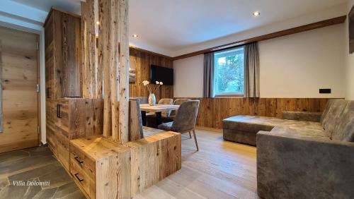 sala de estar con paredes de madera, mesa y sillas en Villa Dolomiti en Ortisei