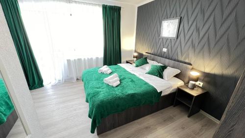 a bedroom with a bed with a green comforter at Casa Ama in Buşteni