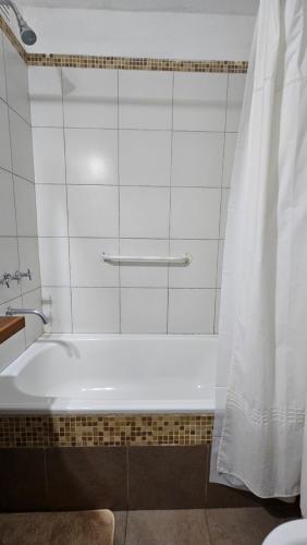 El baño incluye bañera blanca con cortina de ducha. en Dpto. Mendoza en Godoy Cruz