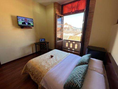 a bedroom with a bed and a tv and a window at Floré Hotel Boutique Cuenca in Cuenca