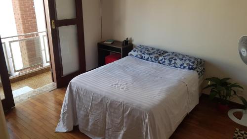 um quarto com uma cama com um cobertor branco e uma janela em Suíte em São Paulo em São Paulo