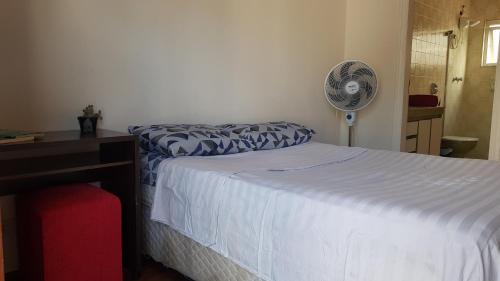 um quarto com uma cama e uma secretária com uma ventoinha em Suíte em São Paulo em São Paulo