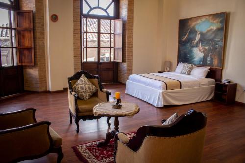 um quarto com uma cama, uma mesa e cadeiras em Floré Hotel Boutique Cuenca em Cuenca