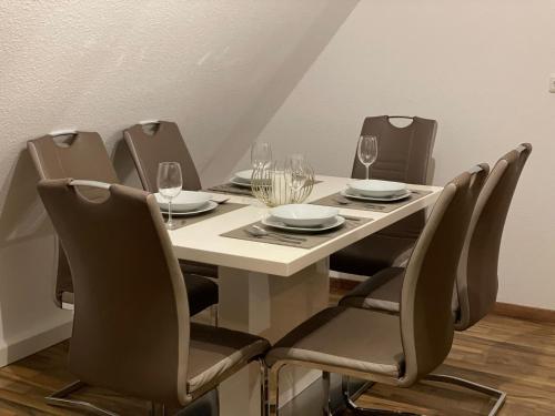 a dining room table with chairs and wine glasses at Komfortable Wohnung in Alzenau