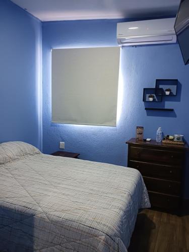 a bedroom with a blue wall with a bed and a window at LA CASA AZUL DE SAMARA in Barrio Nuevo