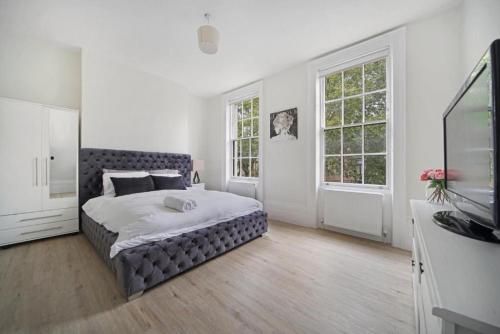 倫敦的住宿－Large 2 Bed Apartment London Camberwell Champion Park Denmark Hill - Great For Long Stays，一间卧室设有一张大床和两个窗户。
