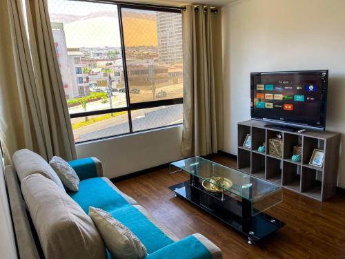 a living room with a blue couch and a tv at Departamento Los Delfines in Iquique
