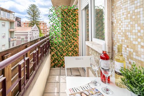 balcón con mesa y 2 copas de vino en Santos Mattos Guesthouse & Apartments by Lisbon with Sintra en Amadora