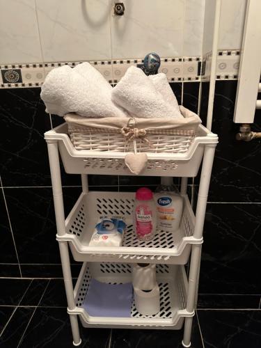 a white rack with towels and other items in a bathroom at Loli apartman in Kraljevo