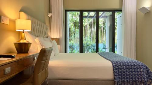 a bedroom with a bed and a desk and a window at Jardim da Batalha Boutique Hotel by Shiadu in Porto