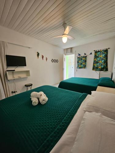 Duas toalhas numa cama verde num quarto em SUÍTES Caminho do Mar em Abraão