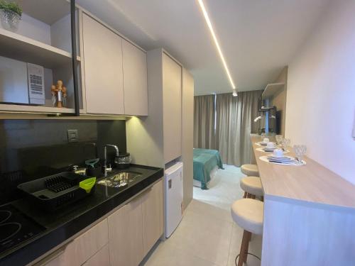 a kitchen with a sink and a counter with stools at Bela Hospedagem - #Sunrise 204 in João Pessoa