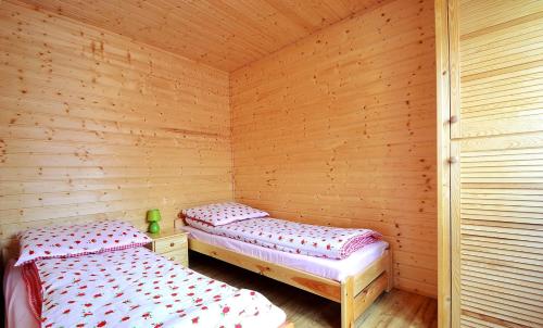 two beds in a room with wooden walls at Domki przy plaży 80 m Jantar w Gąskach in Gąski