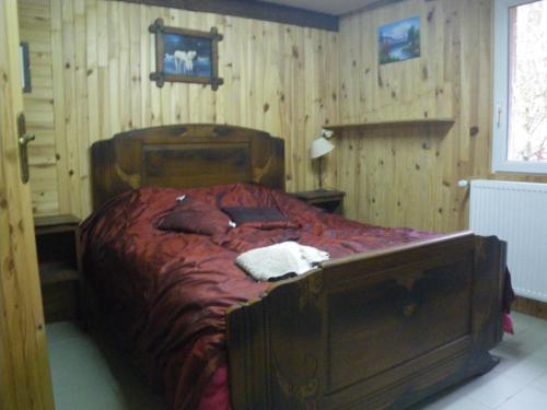 Schlafzimmer mit einem großen Holzbett mit roter Bettwäsche in der Unterkunft Chambre quadruple du grand sapin 