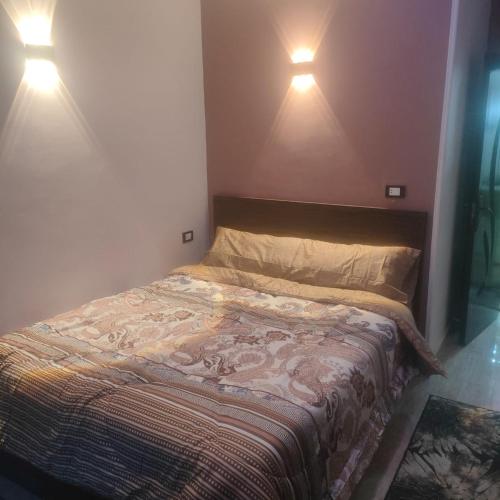 Hurghada Sea View Apartment في الغردقة: سرير في غرفة نوم مع مصباحين على الحائط