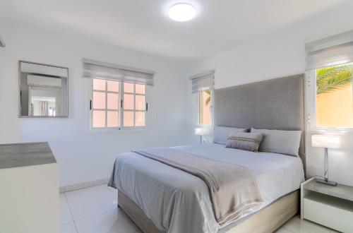 a white bedroom with a large bed and two windows at Mango La Caleta Hideaway in Adeje