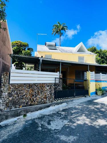 a yellow house with a stone wall and a fence at LE RÊVE EN COULEURS in Saint-Claude