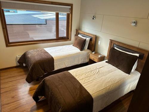 Habitación de hotel con 2 camas y ventana en Portada de Magallanes, en Punta Arenas
