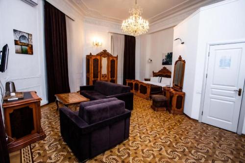 een woonkamer met een bank en stoelen en een slaapkamer bij Malakan Boutique Nizami Hotel in Baku