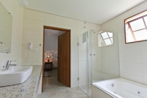 a bathroom with a tub and a shower and a sink at Resort Fazenda 3 Pinheiros in Engenheiro Passos