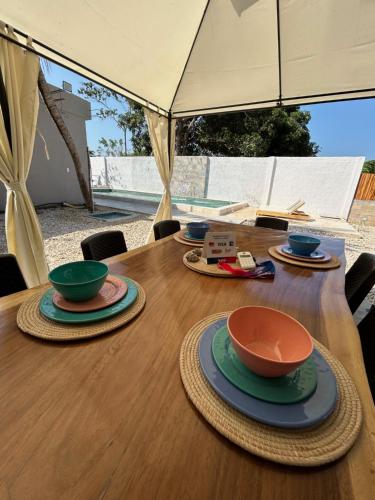 a wooden table with bowls and plates on it at DELAMAR Casa de playa in Coveñas