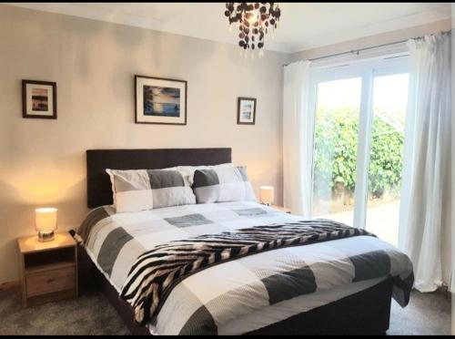 1 dormitorio con cama, ventana y lámpara de araña en Ivy Cottage, en Montrose