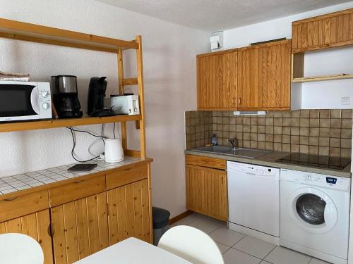 une cuisine avec un lave-linge et un micro-ondes dans l'établissement Charmant 2 pièces cabine 4 pers 3* avec balcon exposé Sud-Est au cœur de Valloire, proche télécabine - FR-1-263-422, à Valloire