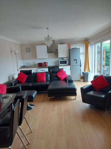 a living room with a black couch and red pillows at Ivy Cottage in Montrose