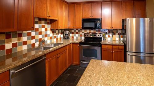 a kitchen with wooden cabinets and stainless steel appliances at Pinnacle Ridge Chalets by Fernie Lodging Co in Fernie