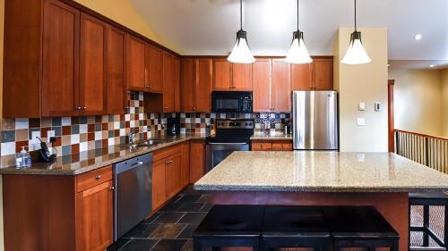 a kitchen with wooden cabinets and a granite counter top at Pinnacle Ridge Chalets by Fernie Lodging Co in Fernie