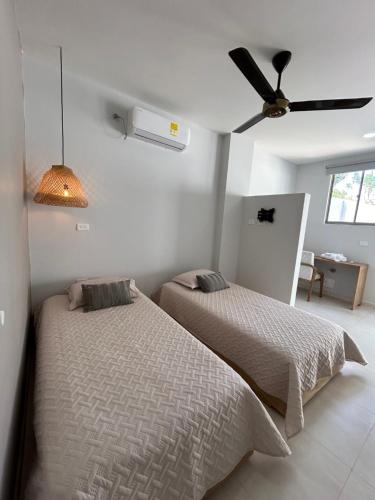 a bedroom with two beds and a ceiling fan at DELAMAR Casa de playa in Coveñas
