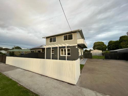 a house with a white fence in a driveway at Irene June Coastal Retreat in Lakes Entrance