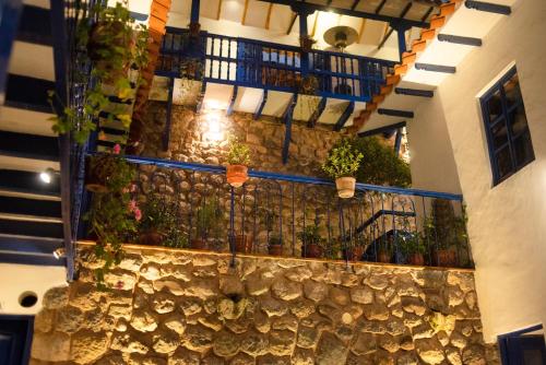 a building with potted plants on a stone wall at Rumi Wasi in Cusco