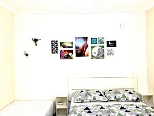 Schlafzimmer mit einem Bett mit Bildern an der Wand in der Unterkunft Apês do Peró - Centro - suíte 03 in Cabo Frio